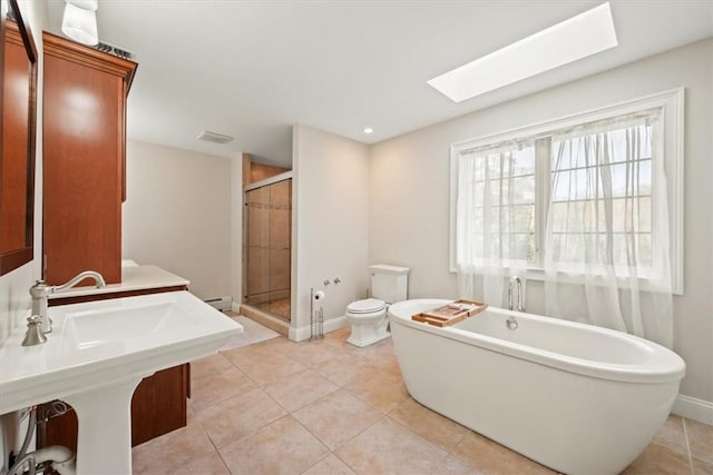 full bathroom featuring a skylight, a baseboard heating unit, tile patterned floors, toilet, and independent shower and bath