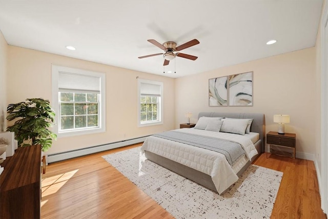 bedroom featuring light hardwood / wood-style floors, ceiling fan, and a baseboard heating unit