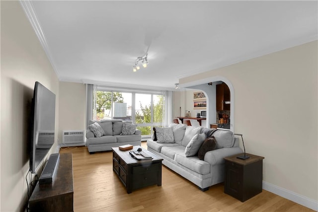 living room with a wall mounted air conditioner, light hardwood / wood-style flooring, and crown molding