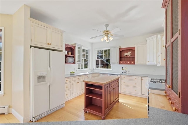 kitchen with white cabinets, ceiling fan, white fridge with ice dispenser, a baseboard radiator, and light hardwood / wood-style floors