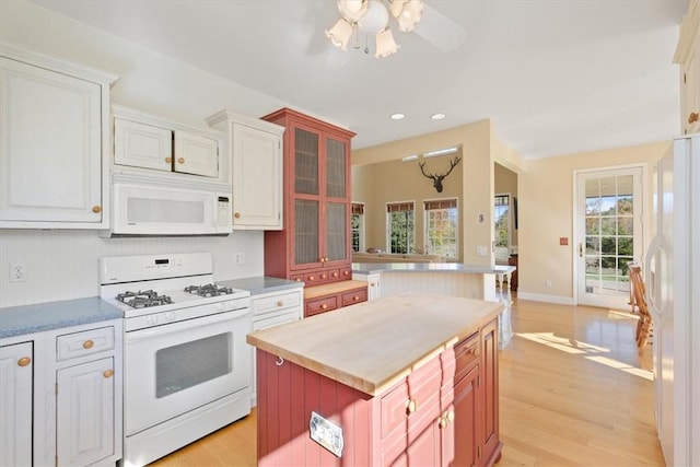 kitchen with a center island, white cabinets, white appliances, and light wood-type flooring