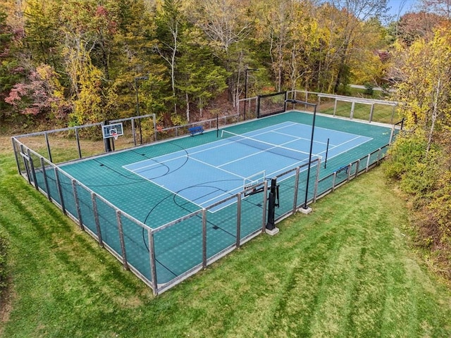 view of tennis court with basketball hoop and a yard