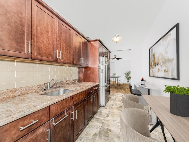 kitchen featuring decorative backsplash, light stone countertops, and sink