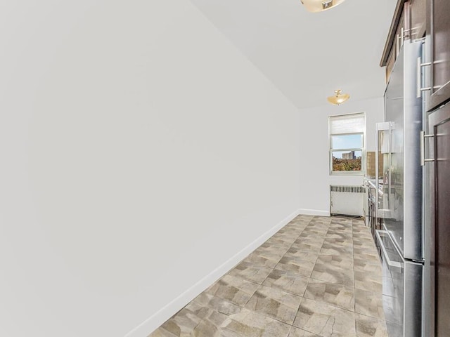 kitchen with high end refrigerator, radiator heating unit, and lofted ceiling