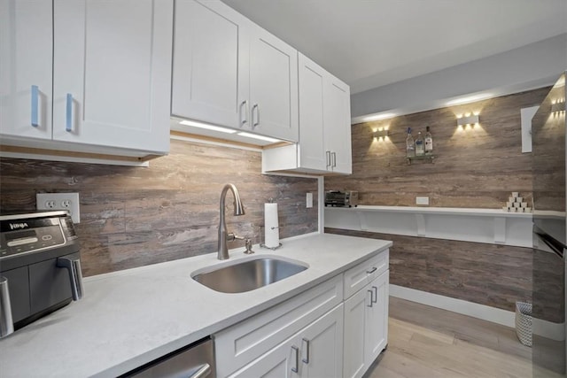 kitchen with backsplash, white cabinetry, sink, and light wood-type flooring