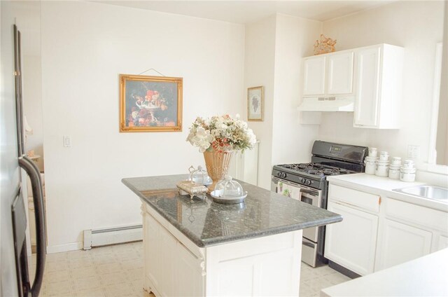 kitchen with white cabinetry, a baseboard heating unit, dark stone countertops, a kitchen island, and appliances with stainless steel finishes