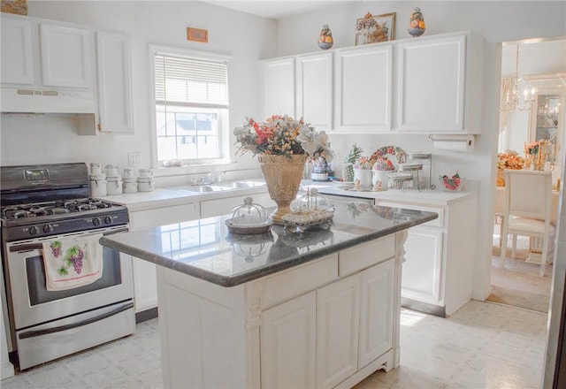 kitchen featuring stainless steel gas stove, sink, white cabinetry, and premium range hood