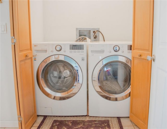 clothes washing area with light tile patterned flooring and washer and dryer