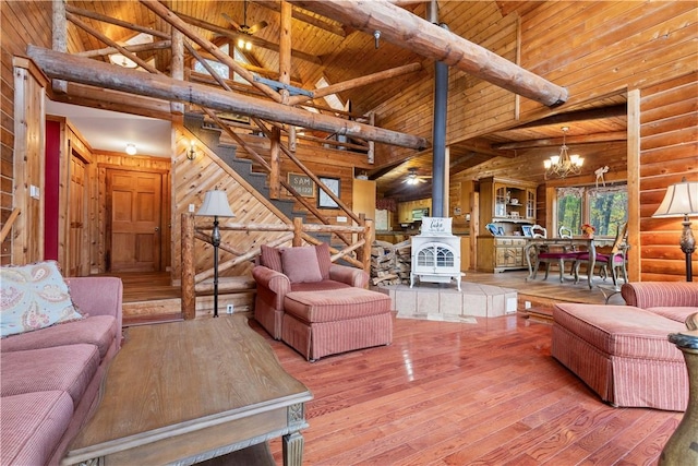 living room with hardwood / wood-style flooring, an inviting chandelier, high vaulted ceiling, wooden ceiling, and a wood stove