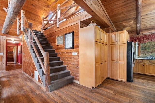 staircase with beam ceiling, wooden walls, hardwood / wood-style floors, and wooden ceiling