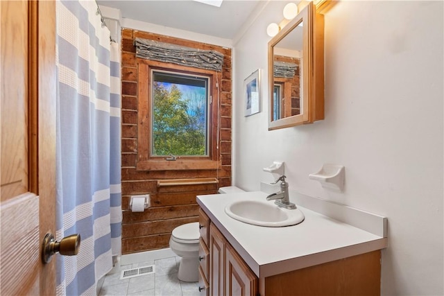 bathroom featuring tile patterned flooring, vanity, wood walls, and toilet