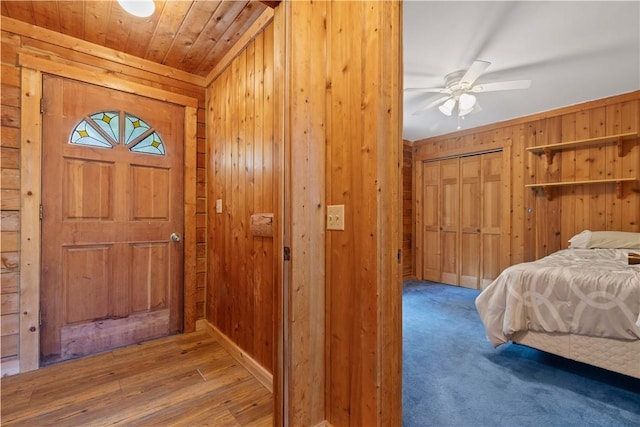 foyer with wood-type flooring, ceiling fan, and wooden walls