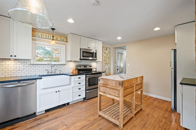 kitchen featuring sink, appliances with stainless steel finishes, pendant lighting, white cabinets, and light wood-type flooring