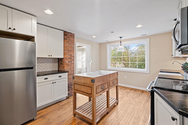 kitchen featuring pendant lighting, white cabinets, stainless steel appliances, and light hardwood / wood-style flooring