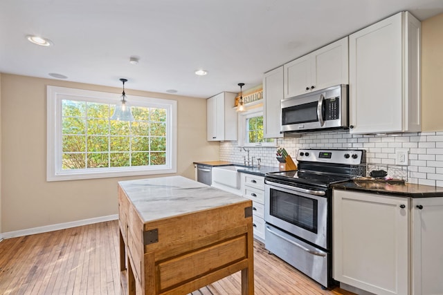 kitchen with a healthy amount of sunlight, white cabinetry, pendant lighting, and appliances with stainless steel finishes