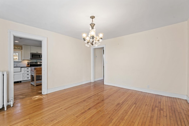 spare room with light wood-type flooring and an inviting chandelier