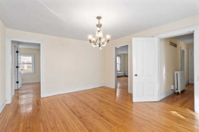 spare room with radiator, a chandelier, and light hardwood / wood-style floors