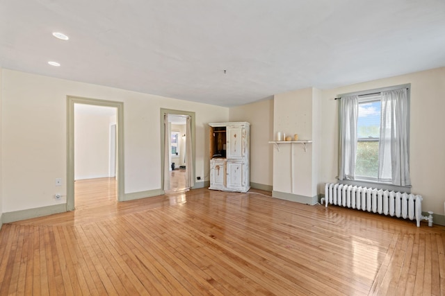 unfurnished living room featuring radiator heating unit and light hardwood / wood-style floors