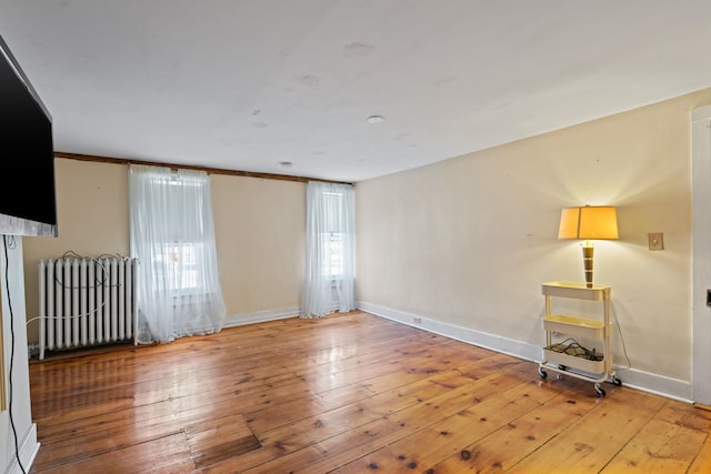 spare room with crown molding, radiator heating unit, and hardwood / wood-style floors