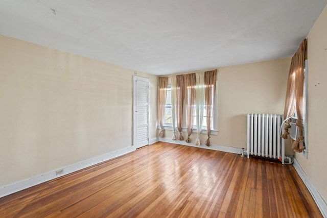 unfurnished room featuring hardwood / wood-style floors and radiator