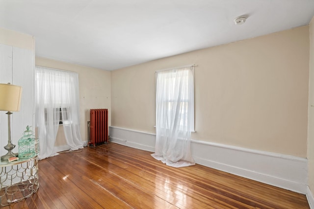 empty room with hardwood / wood-style floors and radiator heating unit