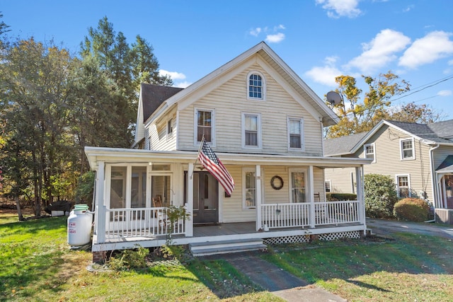 view of front facade with a front yard, a porch, and a sunroom