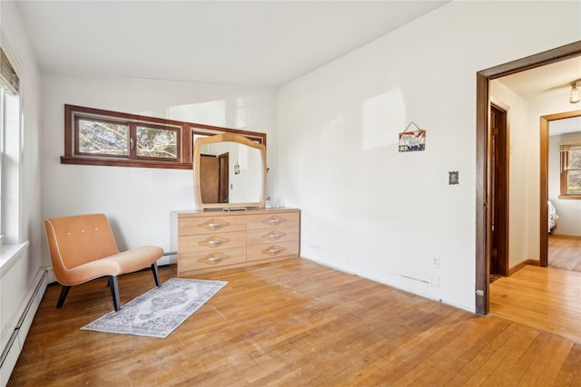 living area featuring wood-type flooring, vaulted ceiling, and a baseboard heating unit