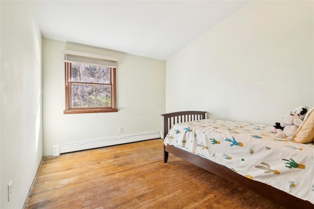 bedroom featuring vaulted ceiling, light hardwood / wood-style flooring, and a baseboard heating unit