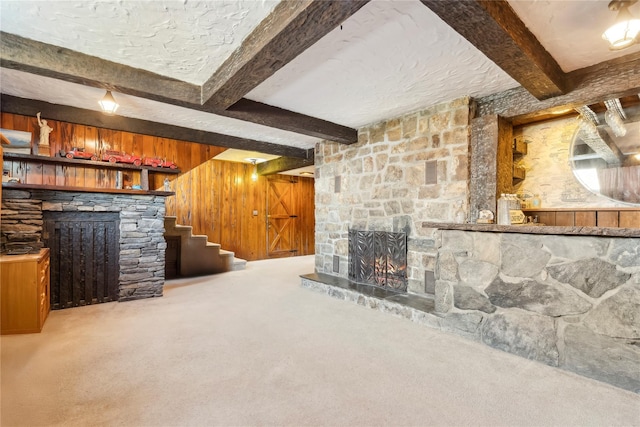 unfurnished living room featuring a fireplace, carpet flooring, beamed ceiling, and wood walls