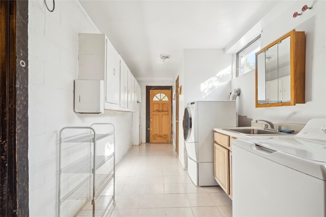 clothes washing area with cabinets, light tile patterned floors, washing machine and dryer, and sink