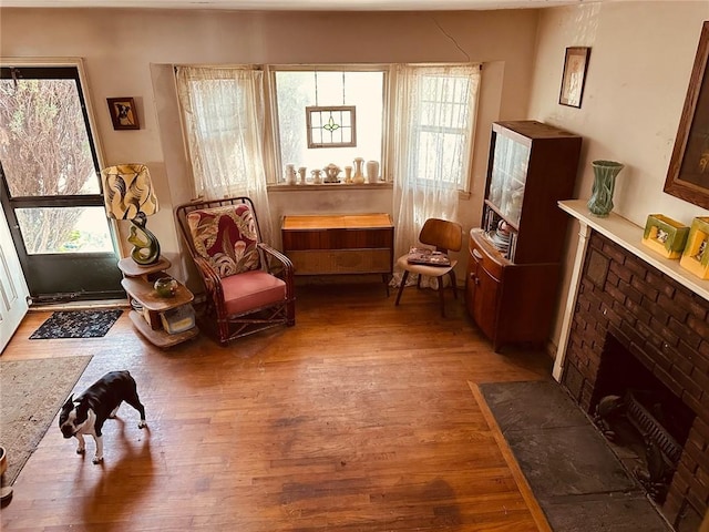 sitting room featuring a brick fireplace and wood finished floors