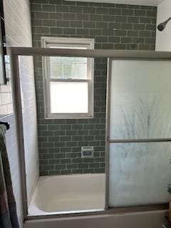 bathroom with combined bath / shower with glass door