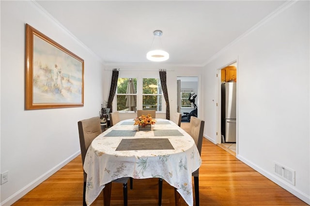 dining area featuring crown molding and light hardwood / wood-style flooring