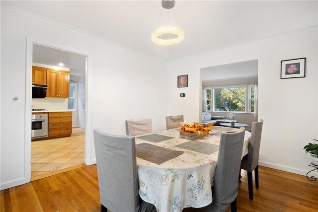 dining space featuring light wood-type flooring and crown molding