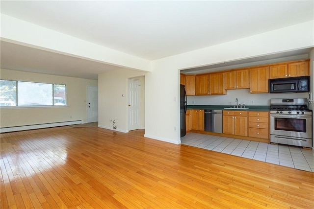 kitchen with sink, light hardwood / wood-style floors, a baseboard heating unit, and black appliances