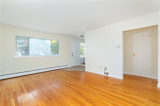 spare room featuring baseboard heating and light hardwood / wood-style flooring