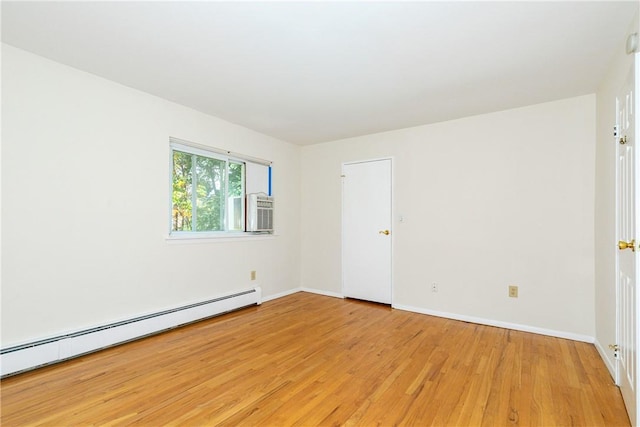 unfurnished room with cooling unit, light wood-type flooring, and a baseboard radiator