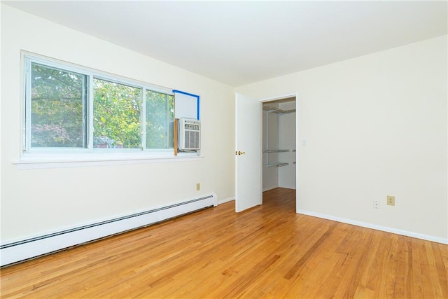 unfurnished bedroom featuring light wood-type flooring and baseboard heating