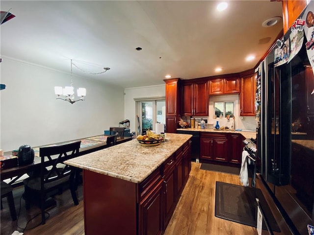 kitchen featuring a center island, hanging light fixtures, ornamental molding, a notable chandelier, and wood-type flooring