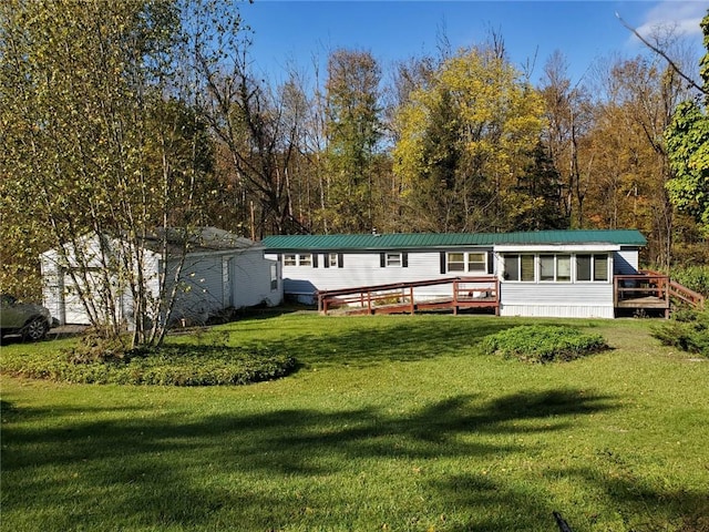 rear view of house featuring a lawn and a wooden deck