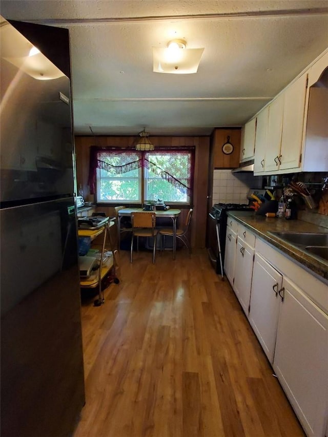 kitchen featuring backsplash, white cabinetry, black gas stove, and light hardwood / wood-style floors