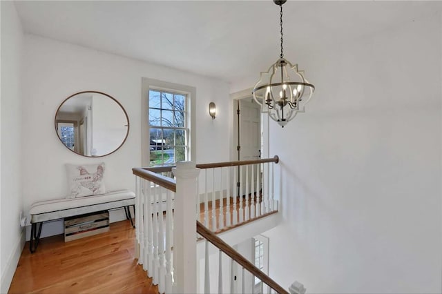 stairway with hardwood / wood-style floors and an inviting chandelier