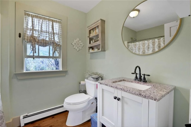 bathroom featuring a healthy amount of sunlight, vanity, toilet, and a baseboard heating unit