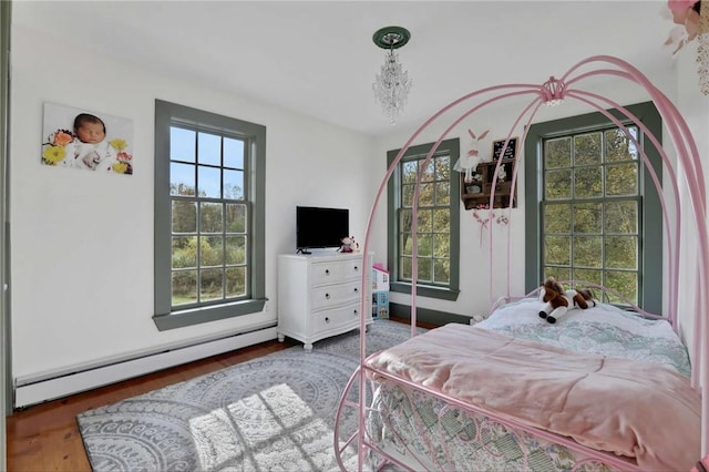 bedroom featuring dark wood-type flooring, an inviting chandelier, and a baseboard heating unit