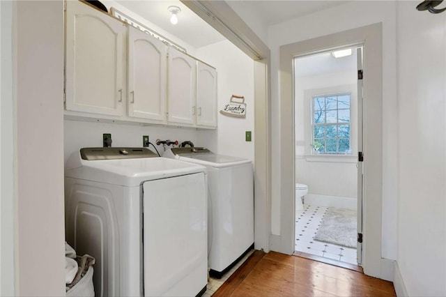 washroom featuring light hardwood / wood-style floors, cabinets, and washing machine and dryer