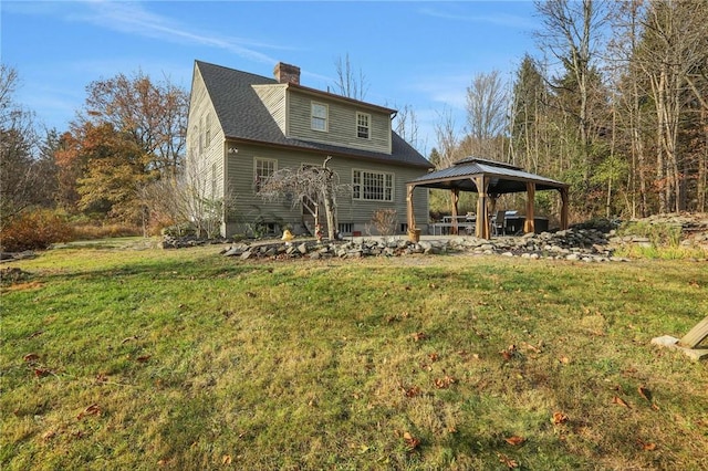 rear view of property featuring a gazebo and a lawn