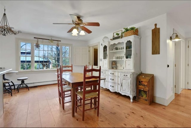 dining area with light hardwood / wood-style floors, ceiling fan, and a baseboard heating unit