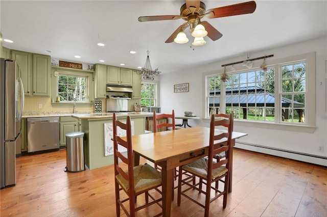 dining space with ceiling fan with notable chandelier, light hardwood / wood-style floors, a baseboard heating unit, and sink