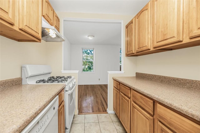 kitchen featuring white appliances, light brown cabinetry, and light tile patterned floors