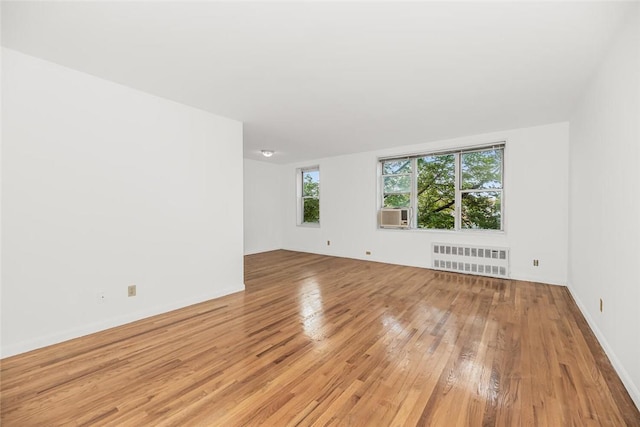 unfurnished room featuring radiator and light hardwood / wood-style flooring